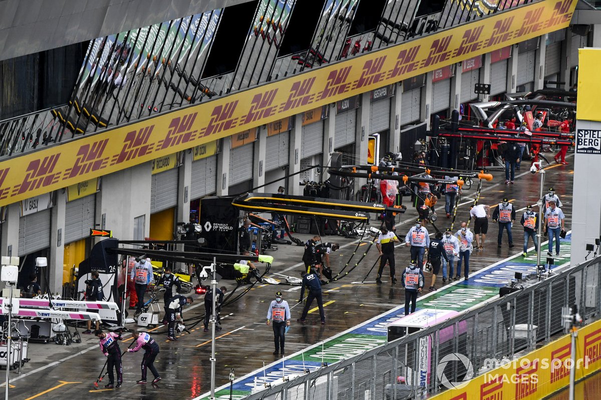 Los mecánicos barren el agua del pit lane