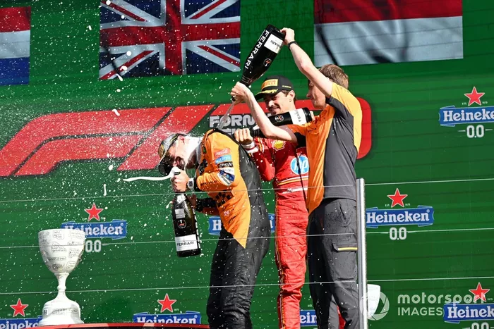 Charles Leclerc, Scuderia Ferrari, 3ª posición, el delegado del trofeo McLaren vierte champán sobre Lando Norris, McLaren F1 Team, 1ª posición, en el podio.