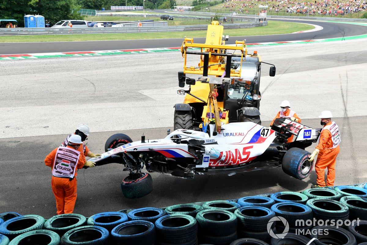 Los oficiales retiran el coche dañado de Mick Schumacher, Haas VF-21, de una barrera de neumáticos tras su accidente en la FP3