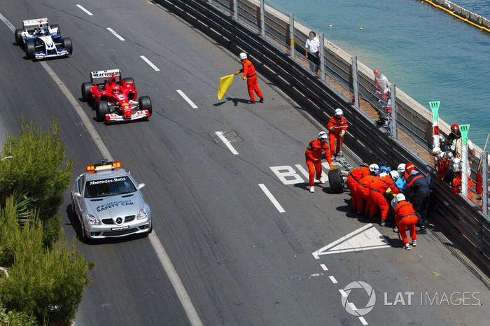 El Renault R24 de Fernando Alonso es atendido por los comisarios tras su accidente a la salida del tunel, y  Michael Schumacher, con el Ferrari F2004, sigue al Safety Car delante de Juan Pablo Montoya, Williams BMW FW26