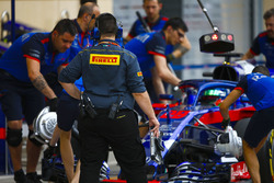 Un ingénieur Pirelli regarde les mécaniciens Toro Rosso pousser Brendon Hartley, Toro Rosso STR13 Honda, dans le garage