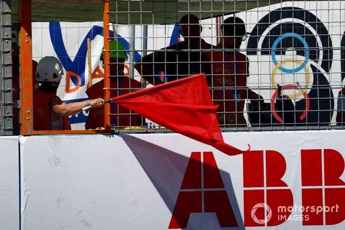 Un comisario muestra la bandera roja tras un fuerte accidente en la vuelta 9.
