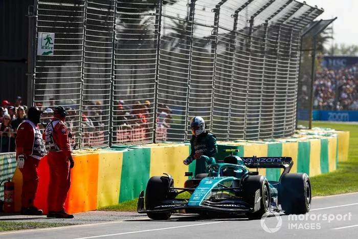 Oficiales de pista asisten a Sebastian Vettel, Aston Martin AMR22, tras abandonar en la FP1