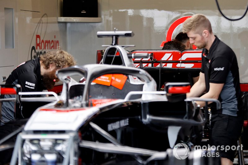 Haas mechanics work on their car in the garage