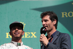 (L to R): Lewis Hamilton, Mercedes AMG F1 on the podium with Mark Webber, Porsche Team WEC Driver / Channel 4 Presenter