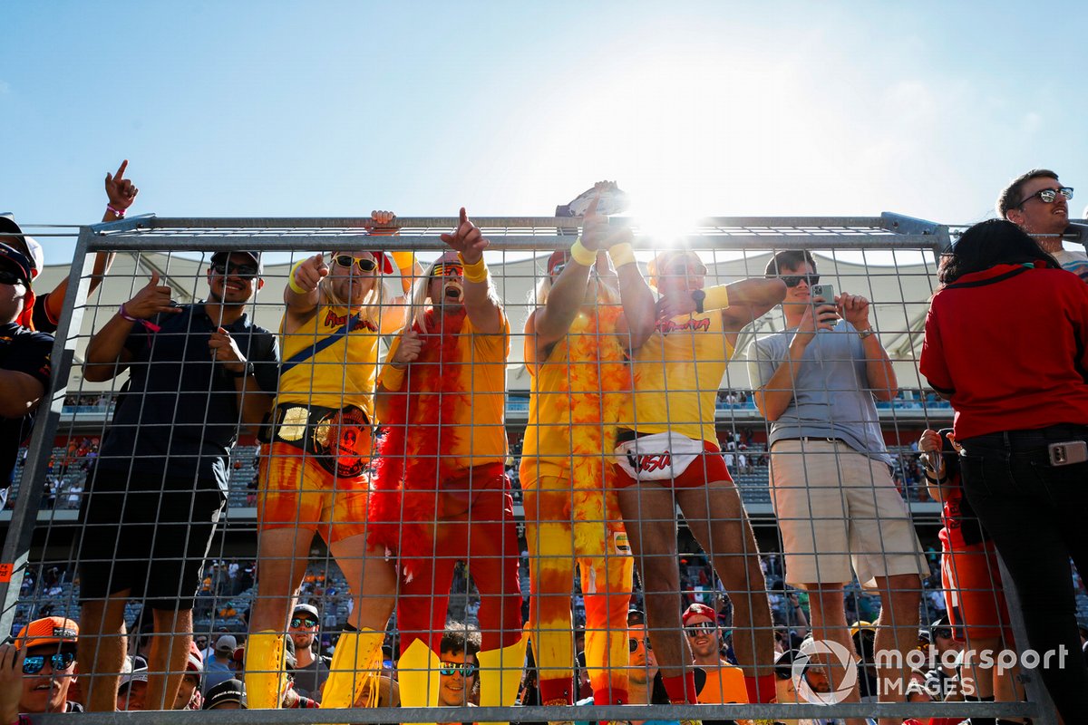 Fans se suben a la valla para ver la ceremonia del podio después de la carrera