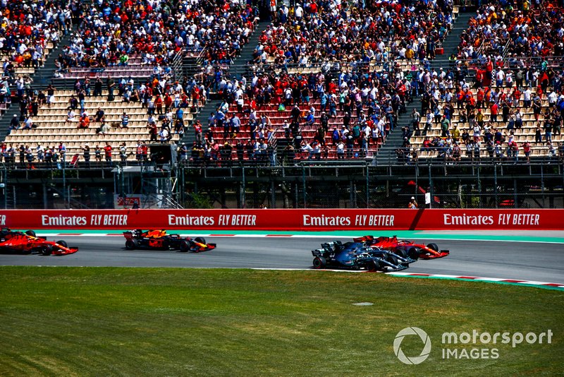 Lewis Hamilton, Mercedes AMG F1 W10, Valtteri Bottas, Mercedes AMG W10 y Sebastian Vettel, Ferrari SF90, compiten codo con codo con Max Verstappen, Red Bull Racing RB15, y Charles Leclerc, Ferrari SF90, en la primera curva al inicio