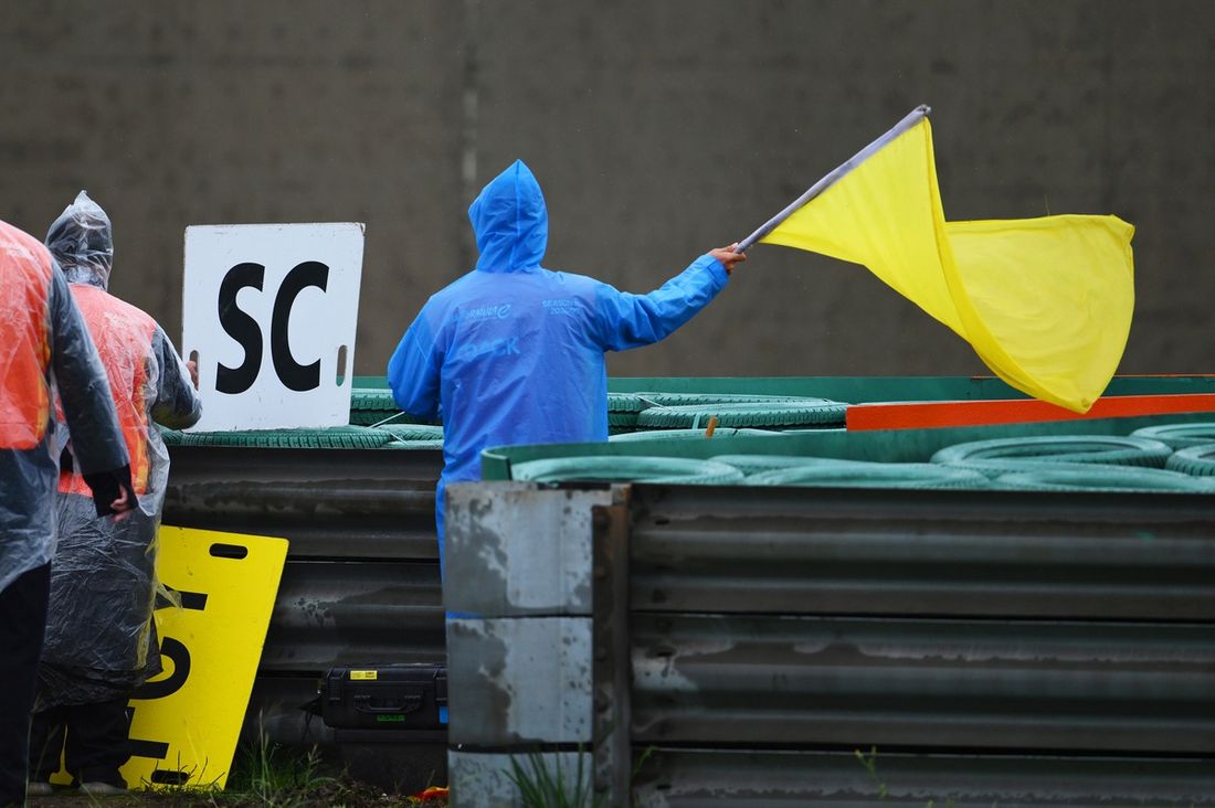 Un comisario de pista agita la bandera amarilla