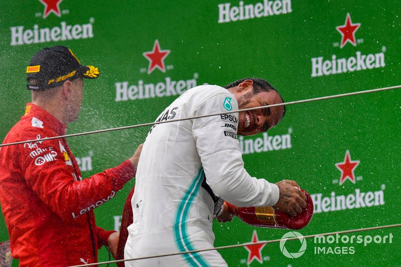 Sebastian Vettel, Ferrari, 3rd position, and Lewis Hamilton, Mercedes AMG F1, 1st position, celebrate with Champagne on the podium