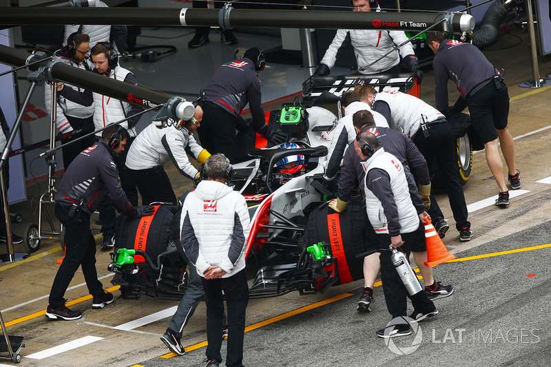 Romain Grosjean, Haas F1 Team VF-18, is attended to by mechanics in the pit lane
