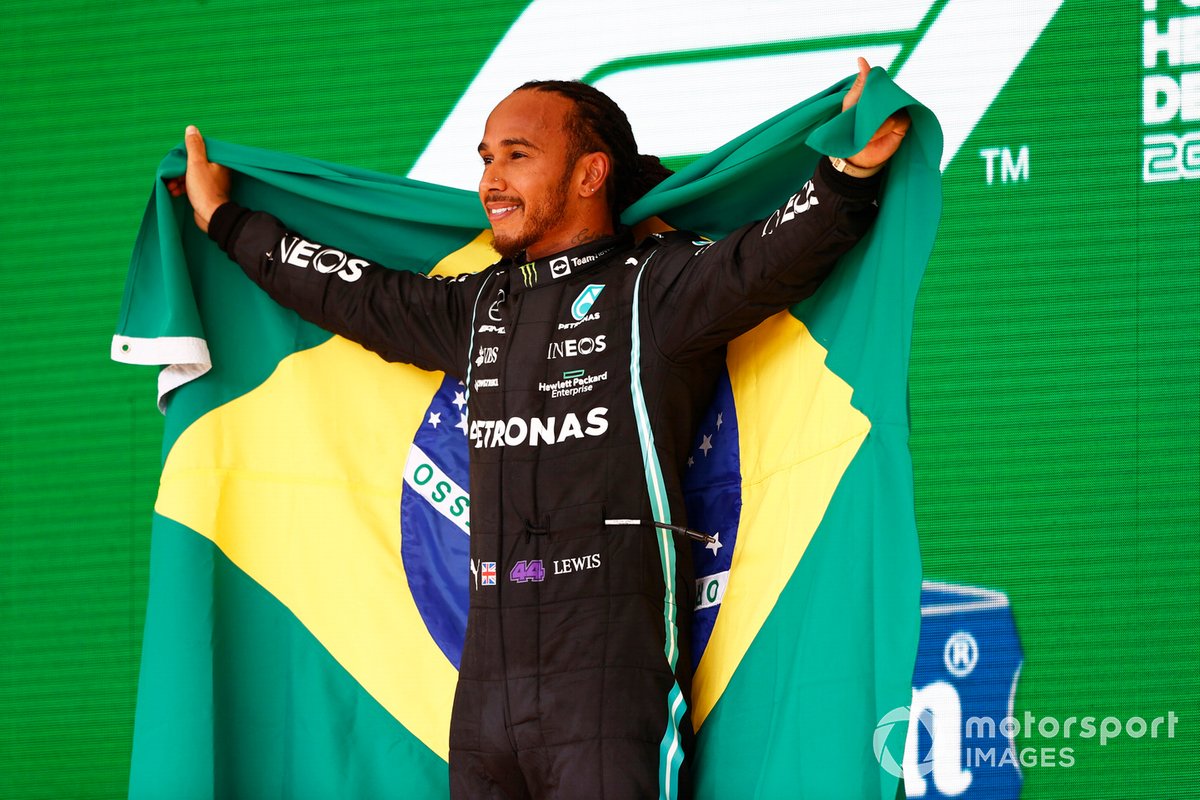 Lewis Hamilton, Mercedes, 1a posizione, festeggia sul podio con una bandiera brasiliana