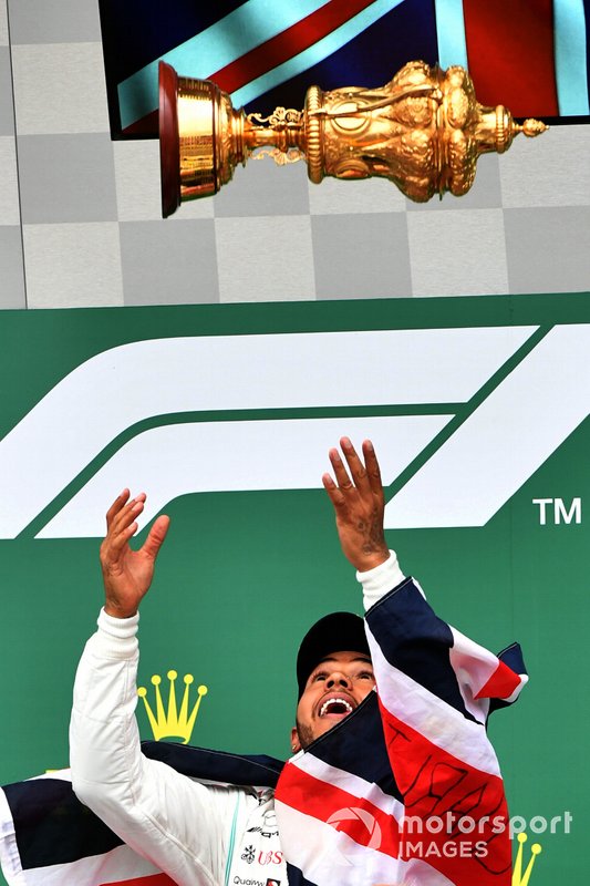 Lewis Hamilton, Mercedes AMG F1, 1st position, tosses his trophy in the air in celebration on the podium