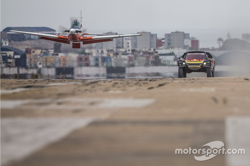 Sebastien Loeb and Daniel Elena of PH Sport make a race with an airplane before the Rally Dakar