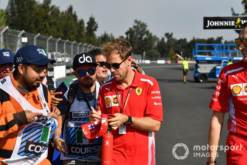 Sebastian Vettel, Ferrari signs autographs for marshals on track walk 