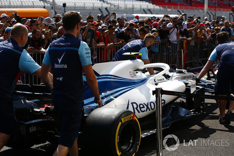 Des mécaniciens de Williams poussent la voiture de Sergey Sirotkin Williams FW41 devant des fans