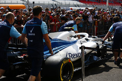 Des mécaniciens de Williams poussent la voiture de Sergey Sirotkin Williams FW41 devant des fans
