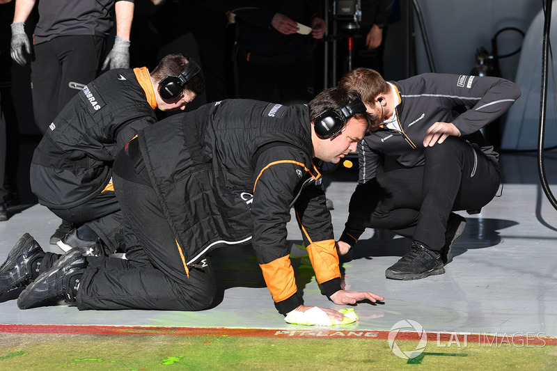 Механики McLaren счищают специальную краску с пола гаража