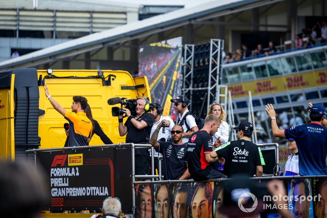 Lando Norris, da McLaren F1 Team, acena para o público, enquanto Lewis Hamilton, da Mercedes-AMG F1 Team, grava com uma câmara de vídeo durante a parada dos pilotos 