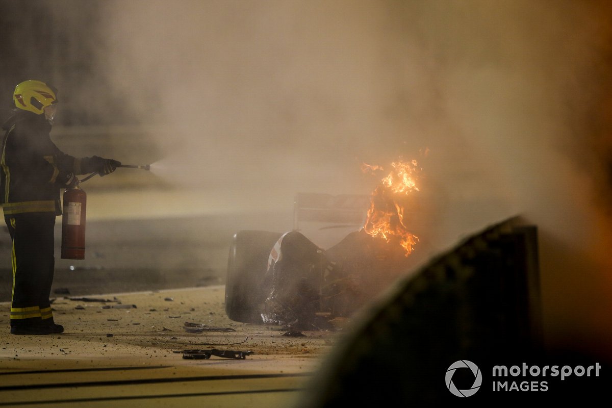 A fire marshal extinguishes the flames after a huge crash for Romain Grosjean, Haas VF-20, on the opening lap