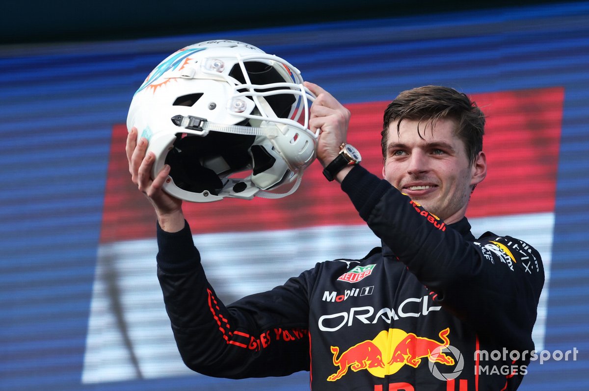 Max Verstappen, Red Bull Racing, 1ª posición, recibe un casco de fútbol de los Miami Dolphins en el podio