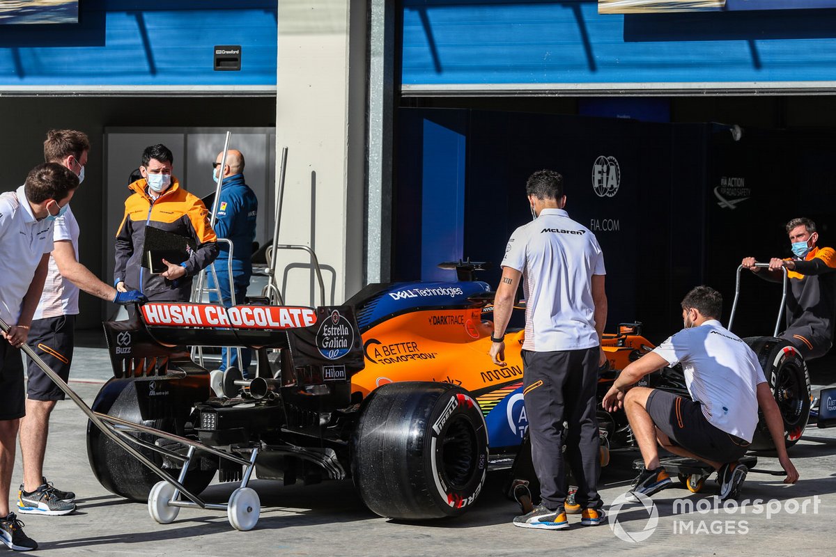 McLaren personnel with one of their cars outside the garage