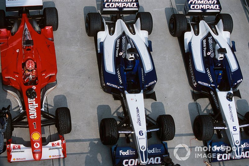 Michael Schumacher gare sa Ferrari F2001 à côté des Williams FW24 de Ralf Schumacher et Juan Pablo Montoya dans le parc fermé