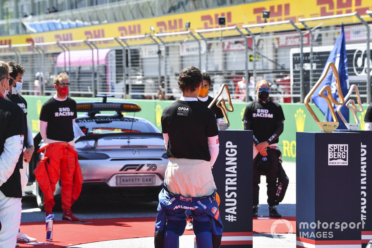 The drivers stand for the national anthems on the grid