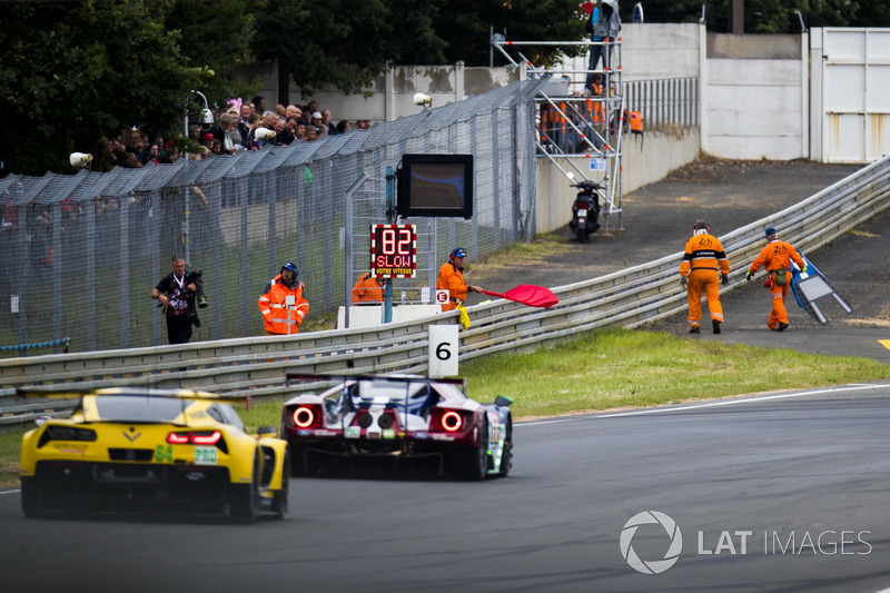 Marshals recover debris from the track during a red flag