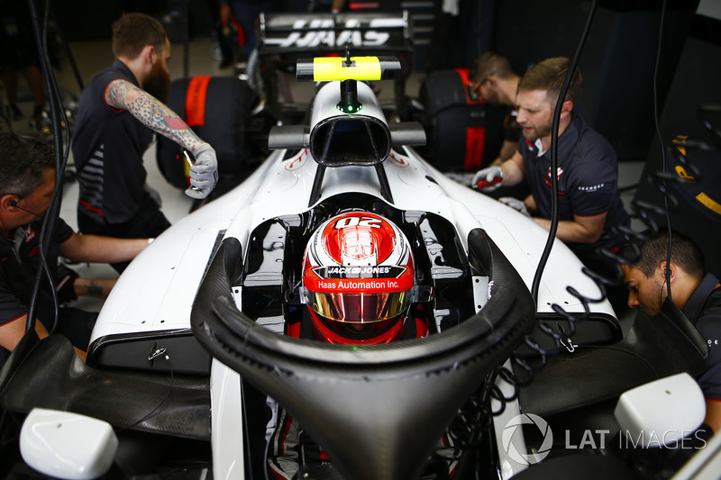 Kevin Magnussen, Haas F1 Team, in cockpit, is attended to by mechanics in the team's garage