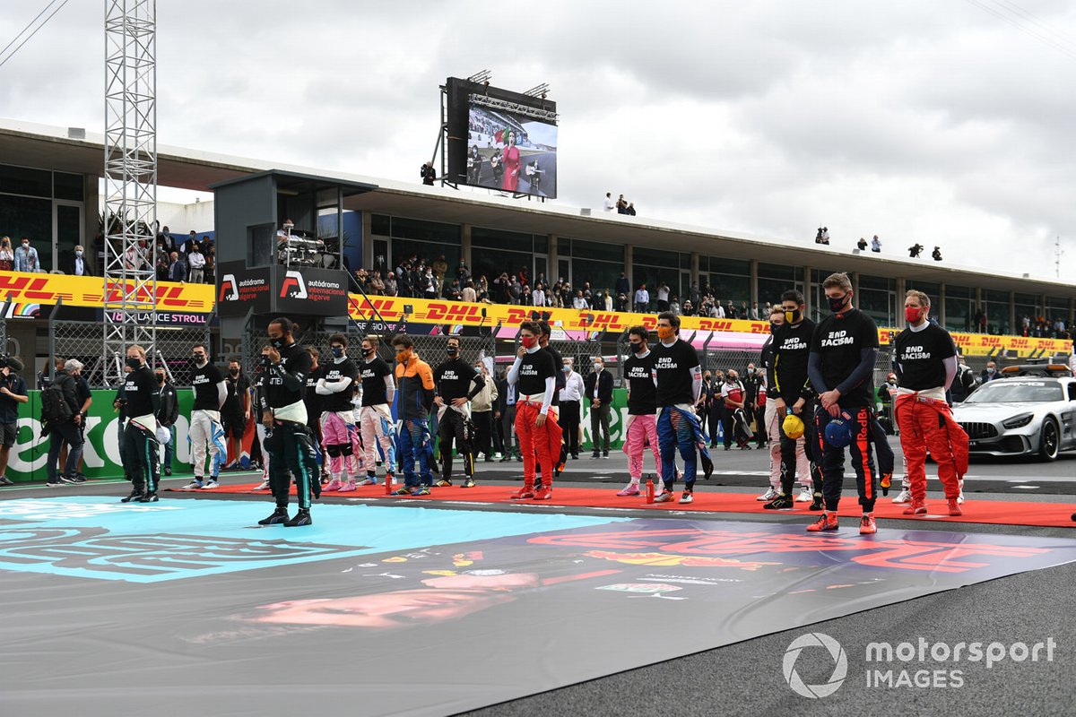 Los pilotos se ponen de pie para el himno nacional antes de la salida en sus camisetas de "End Racism".