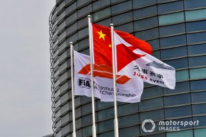 Una bandera china junto a una bandera de Fórmula 1 de la FIA y una bandera de evento de Juss.