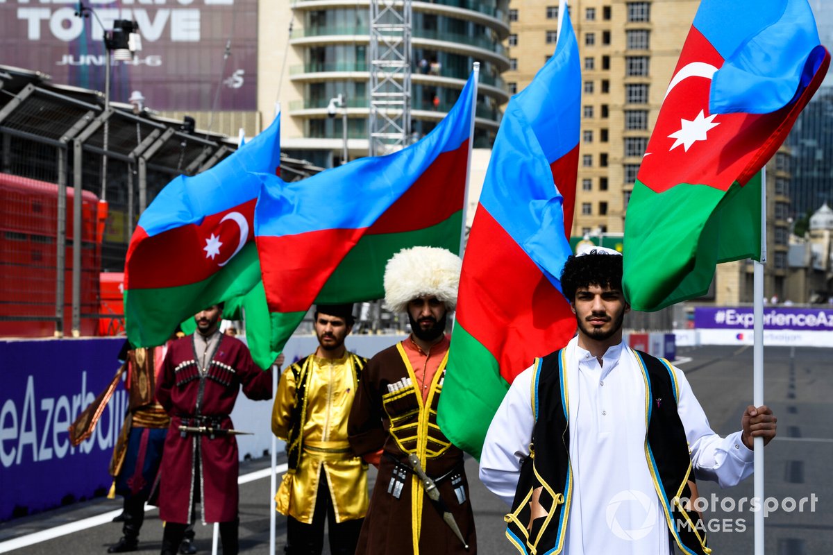 Artistas con trajes tradicionales con banderas de Azerbaiyán en la parrilla