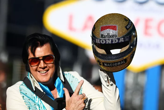 An Elvis Presley impersonator holds up an Ayrton Senna inspired helmet