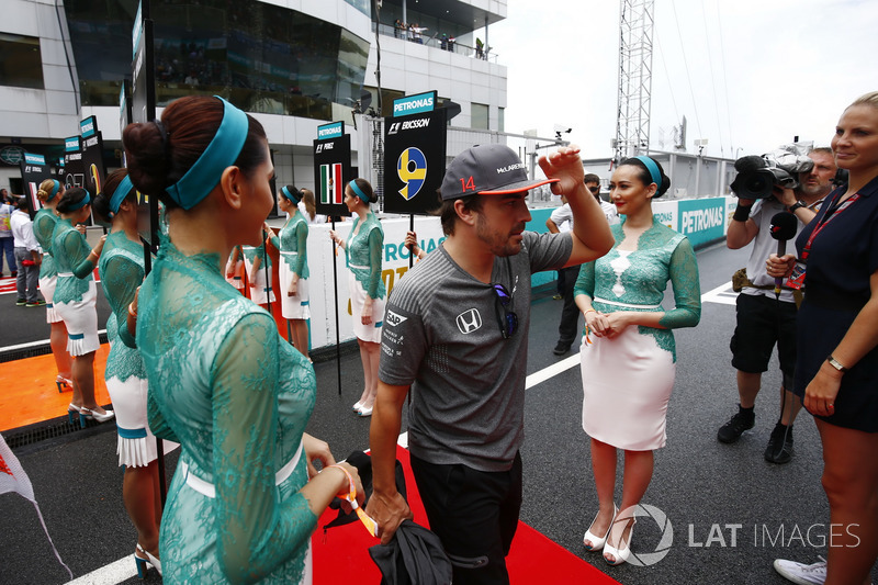 Fernando Alonso, McLaren, walks through a corridor of grid girls