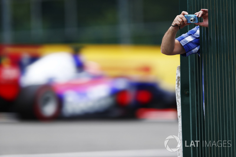 A fan leans out to take some photos as Daniil Kvyat, Scuderia Toro Rosso STR12, passes through the background