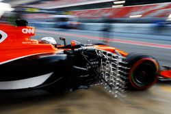 Fernando Alonso, McLaren, exits his garage carrying sensor equipment