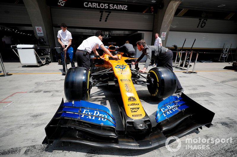 McLaren mechanics push the car of Carlos Sainz Jr., McLaren MCL34, into the garage