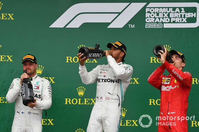 Valtteri Bottas, Mercedes AMG F1, 2nd position, Lewis Hamilton, Mercedes AMG F1, 1st position, and Charles Leclerc, Ferrari, 3rd position, drink from their Champagne bottles on the podium