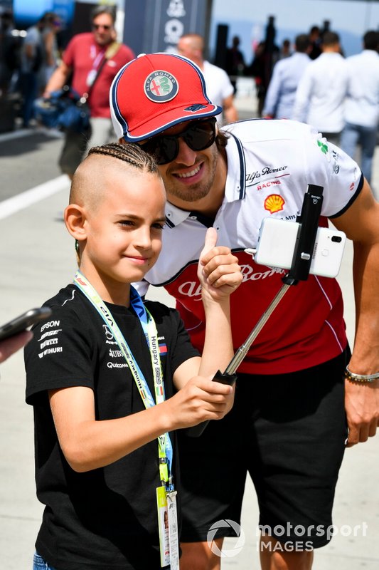 Antonio Giovinazzi, Alfa Romeo Racing poses for a photograph with a young fan in the paddock
