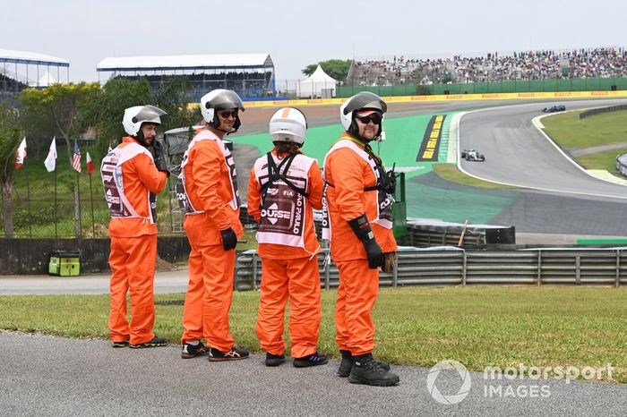 Oficiales de pista esperan el paso de Yuki Tsunoda, AlphaTauri AT03