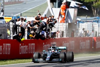 Race Winner drives over the Finish line with the checkered flag being waved with the Mercedes AMG F! Team celebrating