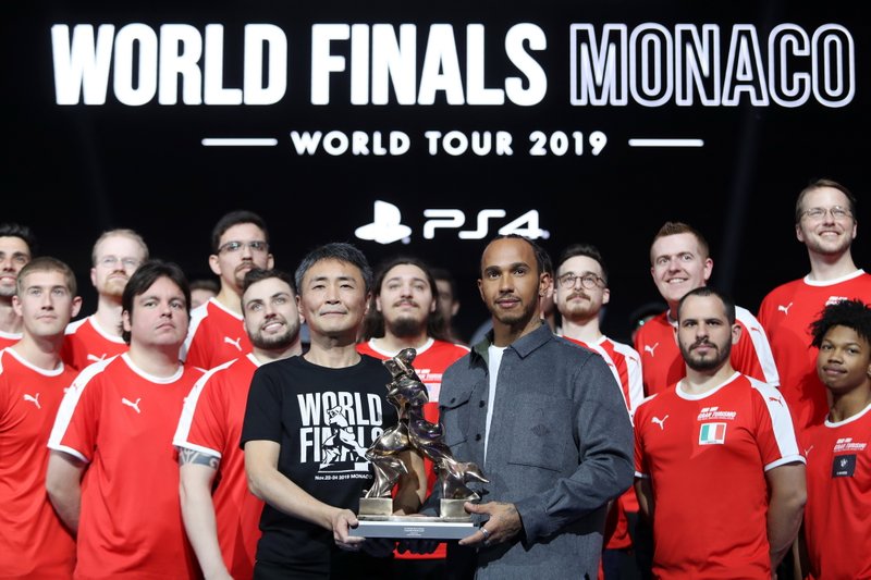 Formula 1 Driver, Lewis Hamilton and producer of Gran Turismo, Kazunori Yamauchi pose for a photo on stage with the competitors