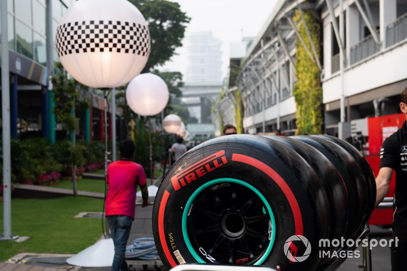 Pirelli tyres are wheeled through the paddock by a Mercedes team member
