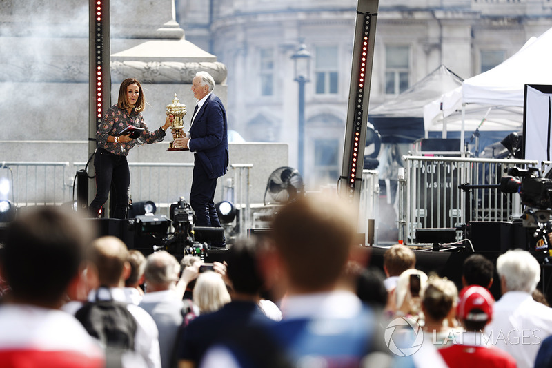 Natalie Pinkham Sky F1, piloto John Watson, y el trofeo del British Grand Prix en el escenario