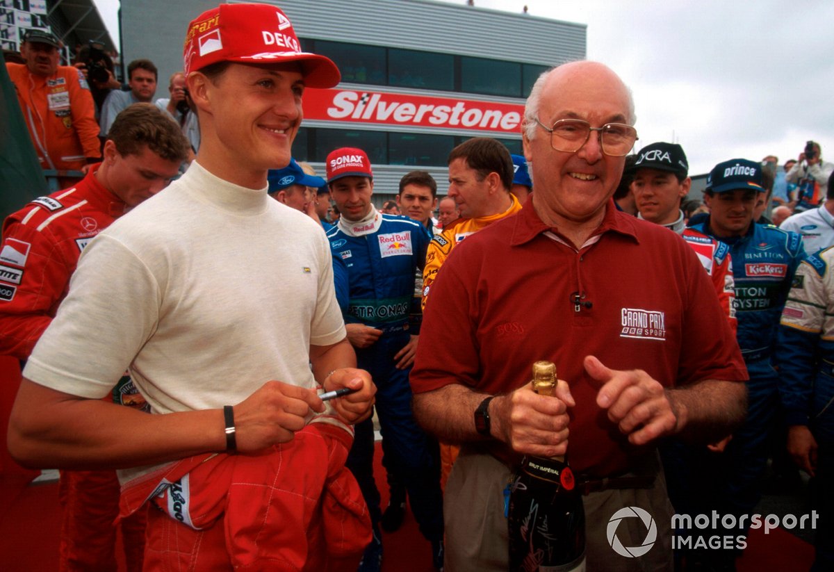 Murray Walker is presented by Michael Schumacher with a bottle of Champagne signed by the Formula One drivers as he prepares to commentate on his final British Grand Prix with the BBC.