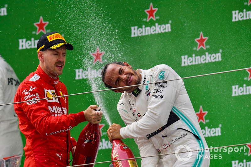Sebastian Vettel, Ferrari, 3rd position, and Lewis Hamilton, Mercedes AMG F1, 1st position, spray Champagne on the podium