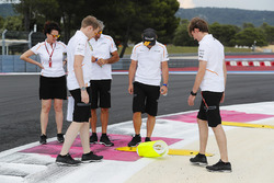 Fernando Alonso, McLaren, inspects a kerb with colleagues