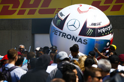 An inflatable in the style of the helmet of Lewis Hamilton, Mercedes AMG F1, is carried by a fan