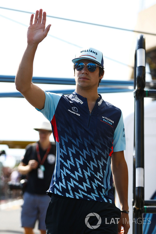 Lance Stroll, Williams Racing, waves while walking in the pit lane
