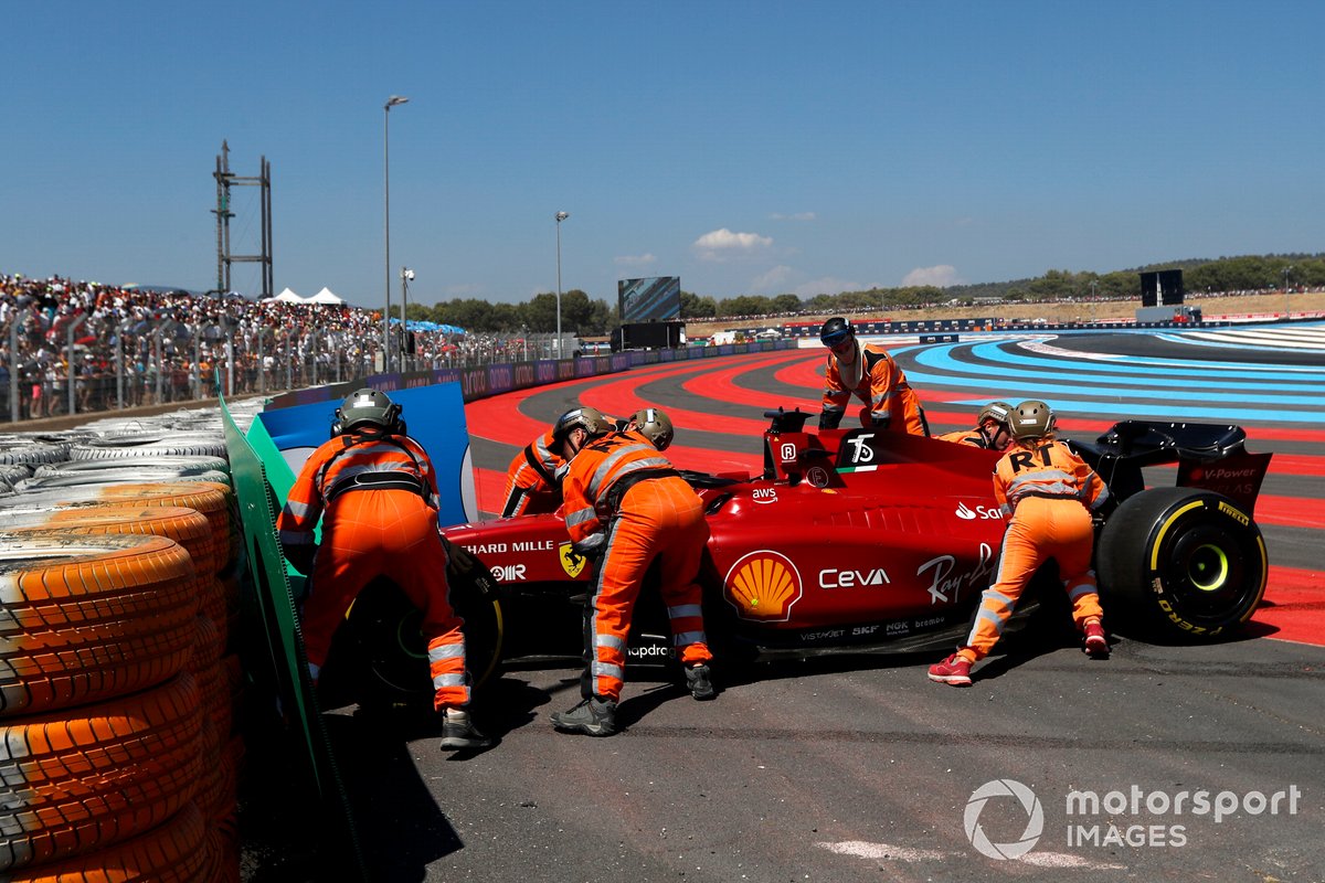 Leclerc's Ferrari is moved behind the barrier after his crash from the lead